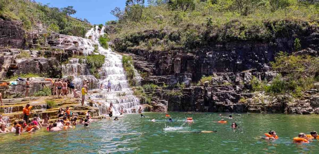 Pessoas se divertindo em uma cachoeira em Capitólio.