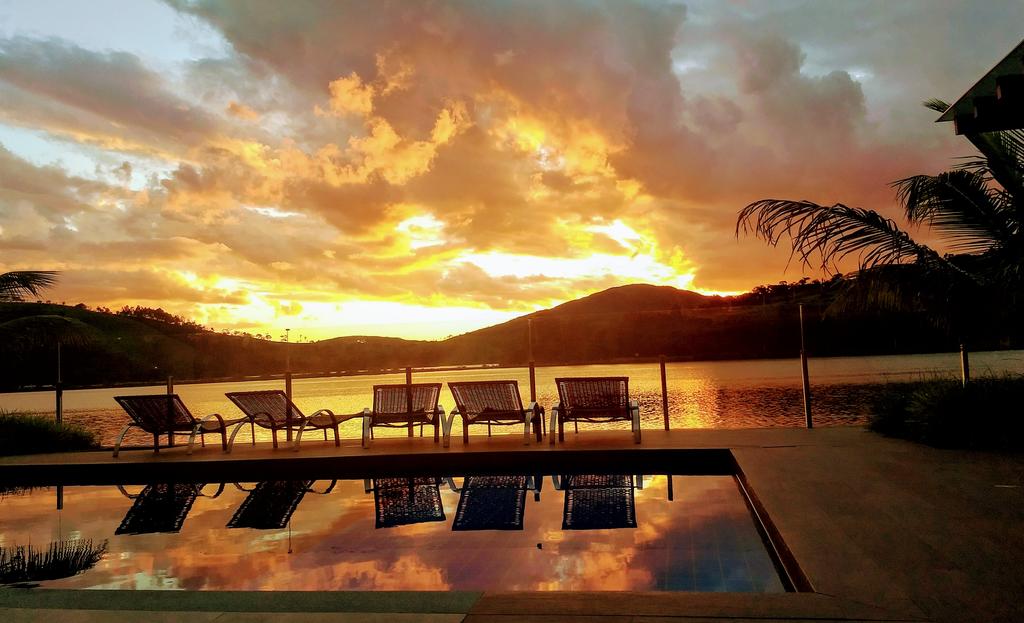 Imagem de Capitólio onde fica com um por do sol ao fundo e em primeiro plano a  piscina de um hotel em Capitólio.