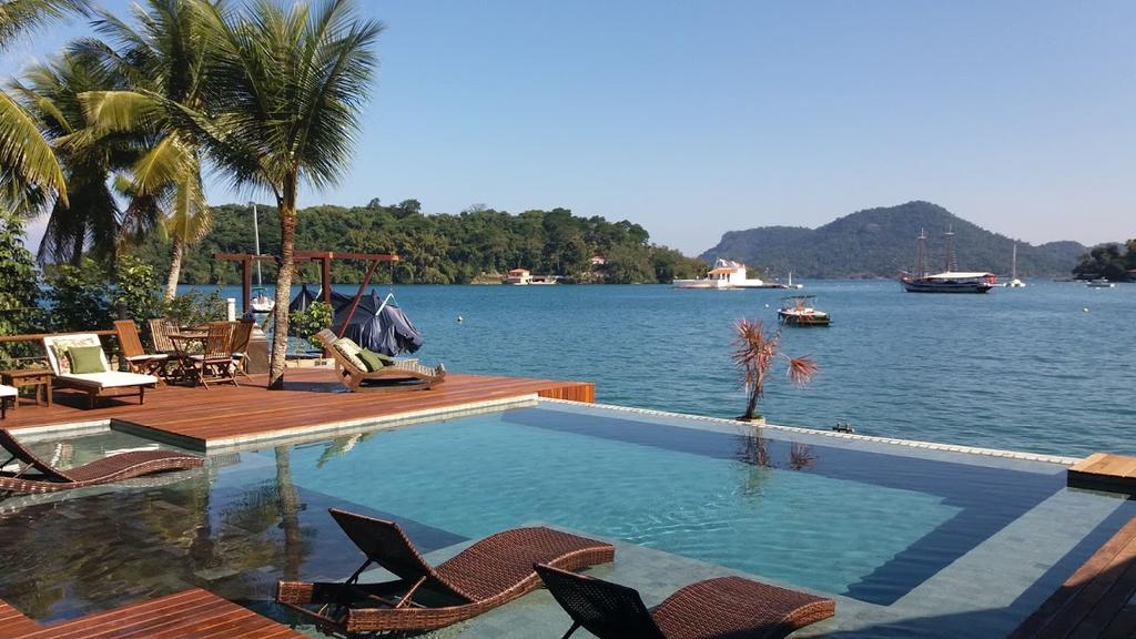 Piscina cercada por cadeiras elegantes a poucos metros da praia em o que fazer em Angra dos Reis