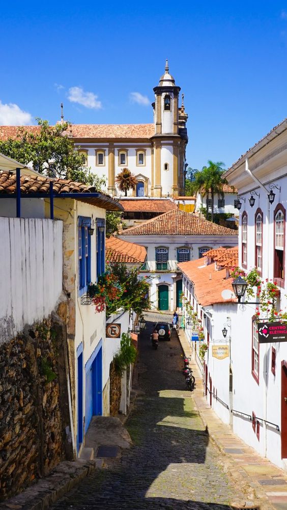 Uma rua cercada por casas colonias a sombra da Igreja de São Francisco de Assis.