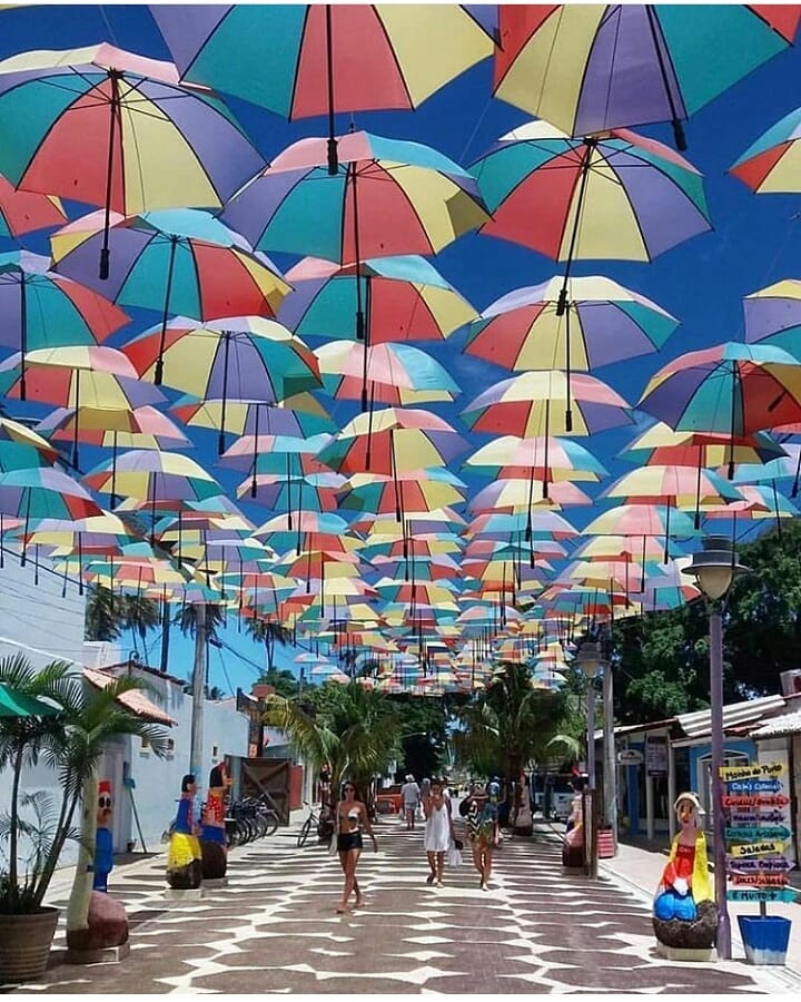 Rua principal de Porto de Galinhas, cheia de guarda sois coloridos e pessoas caminhando.