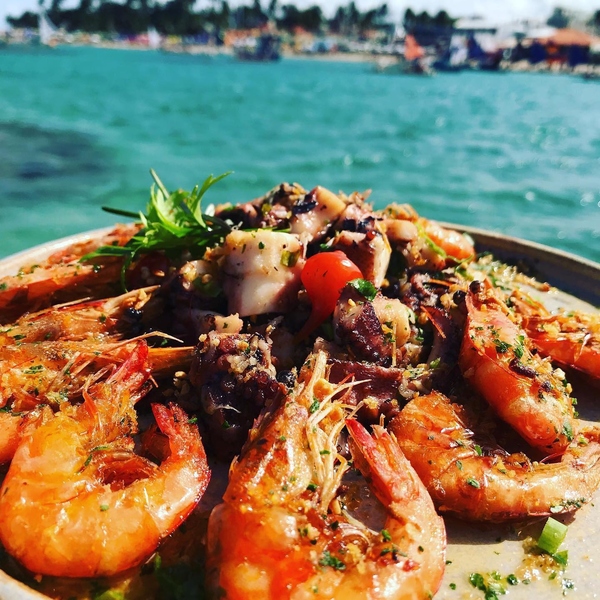 Prato delicioso de camarões e temperos a frente do mar azul de porto de galinhas