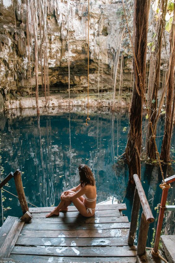 Mulher sentada em plataforma de madeira observando um cenote