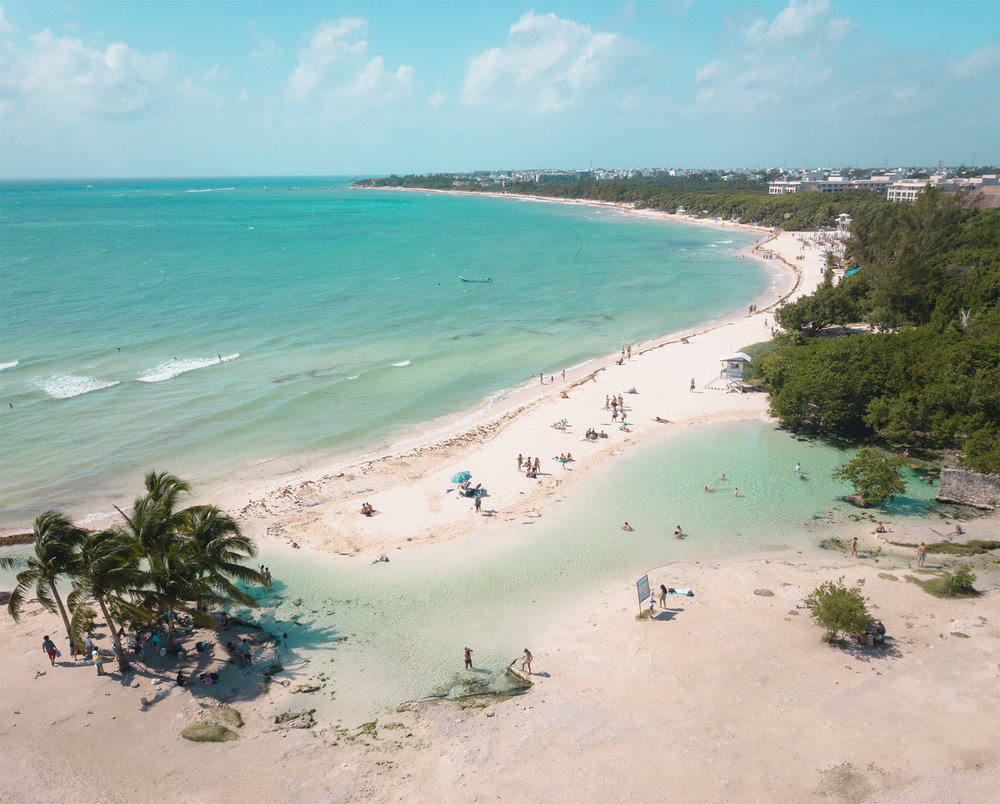 Visão distante de Punta Esmeralda, com sua água esverdeada, areia branca e mata verde em praia del carmen