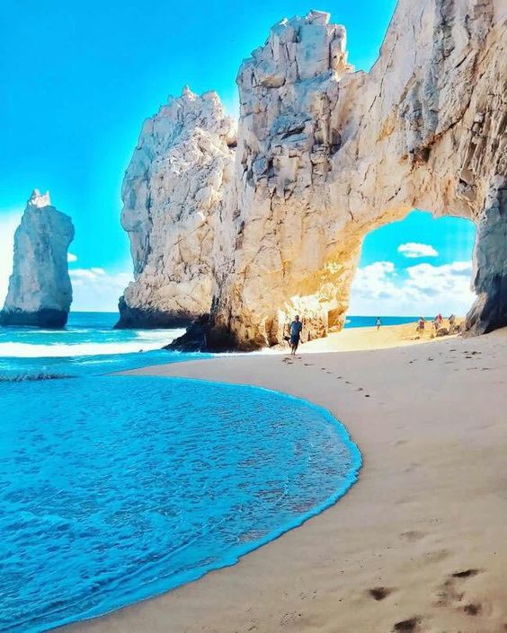 Mar azul, areia branca e um rocha erodida com uma passagem no meio que é o marco de Los Cabos, em turismo no méxico