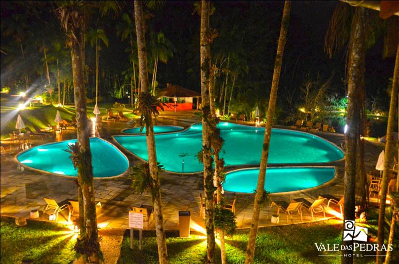 Conjunto de piscinas ricamente iluminadas por holofotes cercados por árvores em hotéis e resorts em santa catarina