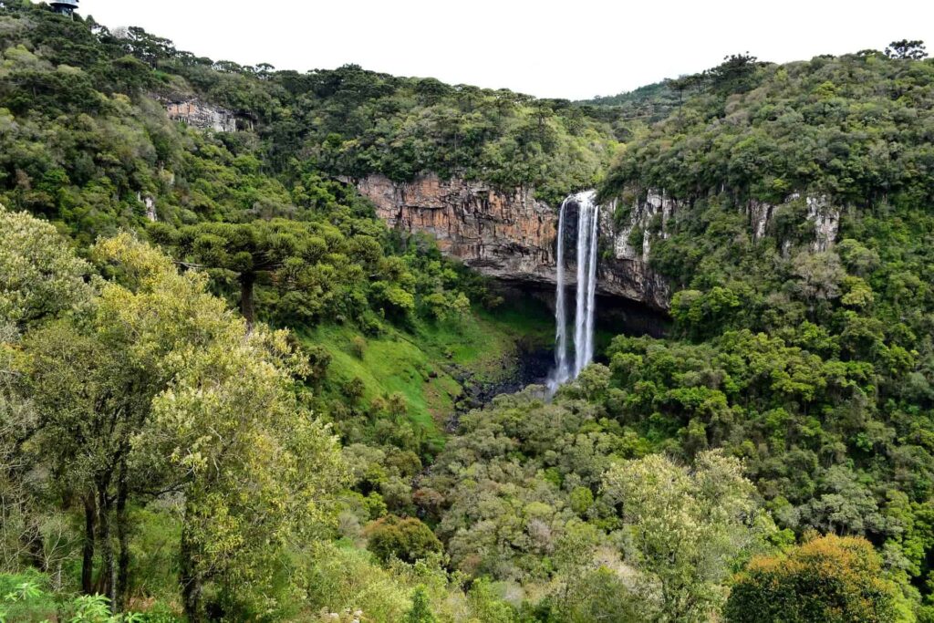 Vista a distância da cascata do caracol, cercada por vegetação verdinha em gramado pontos turísticos