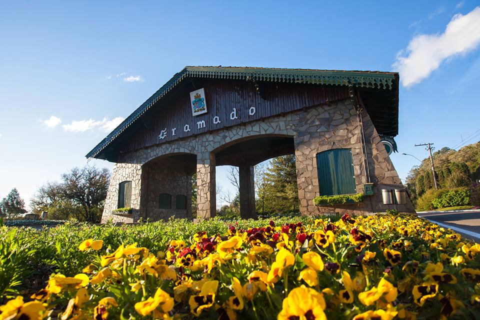 Portal de entrada da cidade de Gramado, cercado s de flores sobre a luz do sol