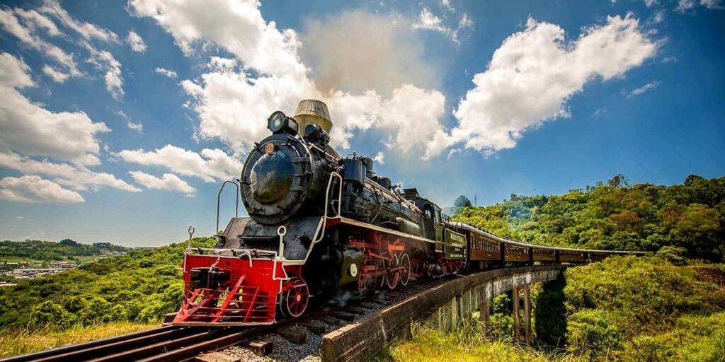 Maria fumaça percorrendo seu caminho sob uma ponte largando fumaça em um céu azul claro em gramado pontos turísticos