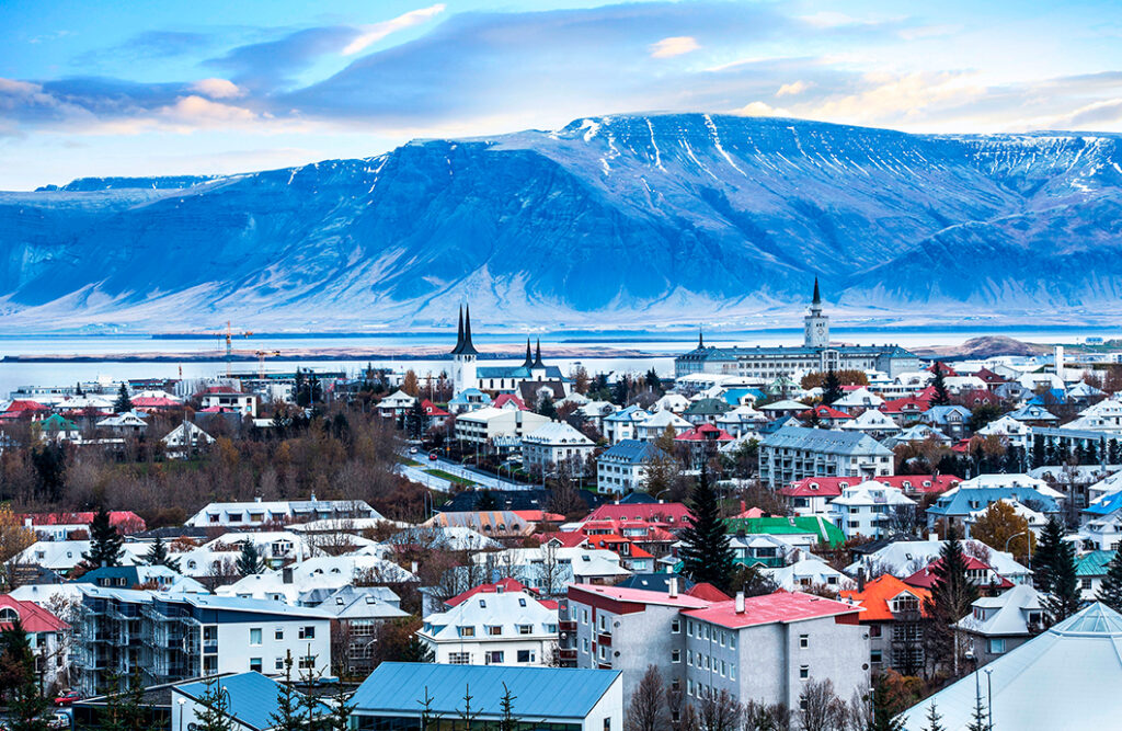 Cidade gelada, com pinheiros e neve aos pés de enormes montanhas azuladas cobertas de gelo em um destino de inverno