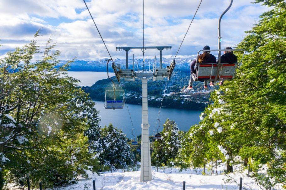 Torre de bondinho em uma pista  de esqui coberta de neve e cercada por árvores em um destino de inverno