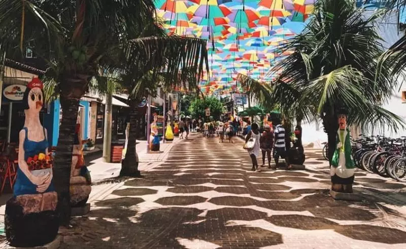 Rua principal do centrinho de Porto de Galinhas, com estátuas divertidas, coqueiros e lojinhas por todos os lados.