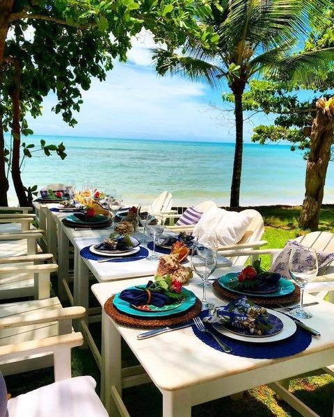 Mesa feita para receber pratos típicos coberta por coqueiros em Trancoso praia do Espelho